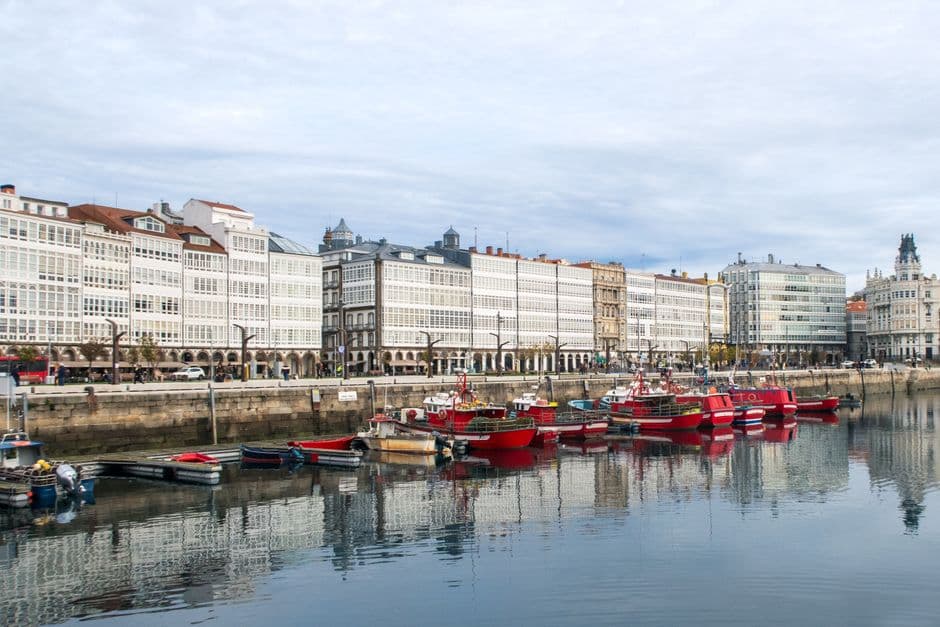Barcos coloridos navegando por un canal con casas estrechas, en la sala de chat de Culleredo