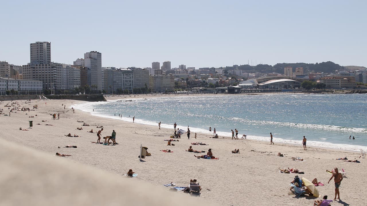Playa de arena con olas del Atlántico bajo cielo despejado, en el chat de Cambre