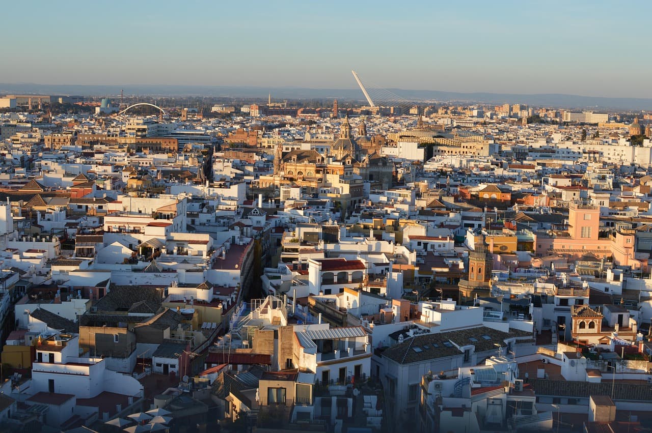 Vista de Sevilla con torres y río bajo cielo azul, en el chat de Arahal