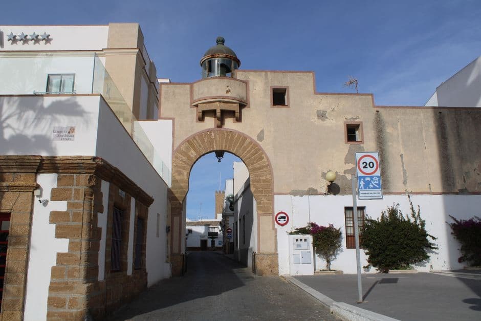 Puerta de entrada de calle empedrada con casas blancas y flores, en el chat de Torredembarra