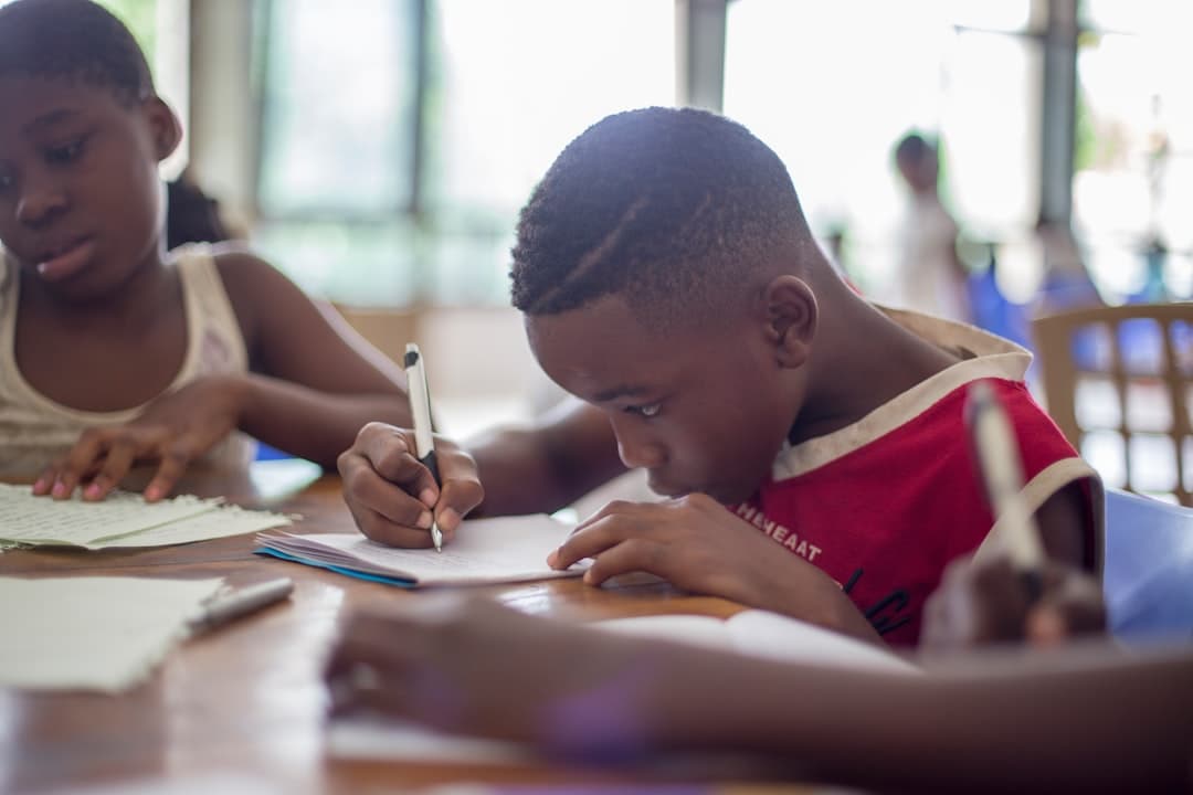 Niño escribiendo en papel cerca de una niña, en la sala de chat de Guinea Ecuatorial