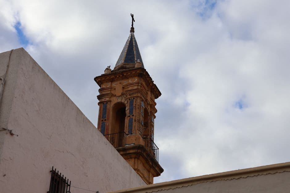 Torre histórica de una capilla bajo cielo nublado en Andalucía, en el chat de Torredelcampo