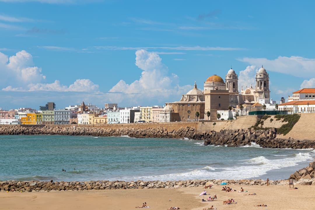 Playa con arena, edificios y mar azul al fondo, en la sala de chat de Cádiz