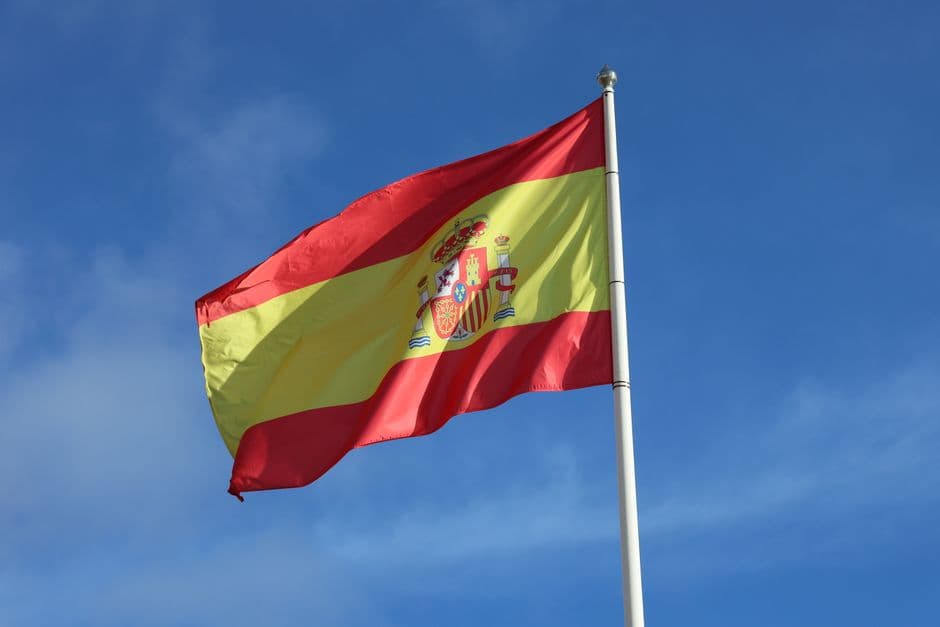Bandera española ondeando bajo un cielo azul despejado, en la sala de chat de El Espinar