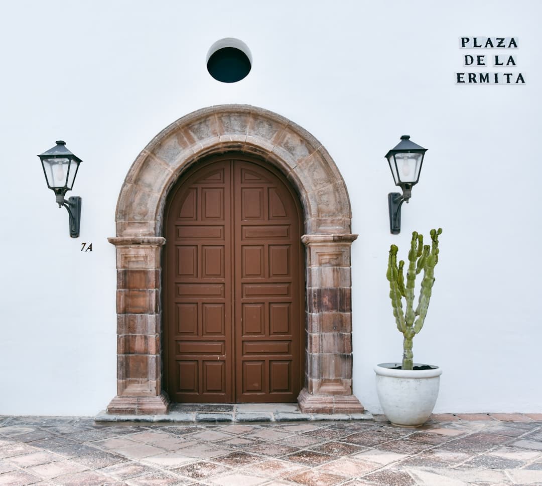 Puerta arqueada marrón con faroles y cactus en maceta, en el chat de Xinzo de Limia