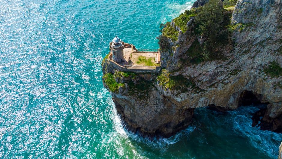 Faro blanco sobre acantilado rocoso con vista al mar, en la sala de chat de Santoña