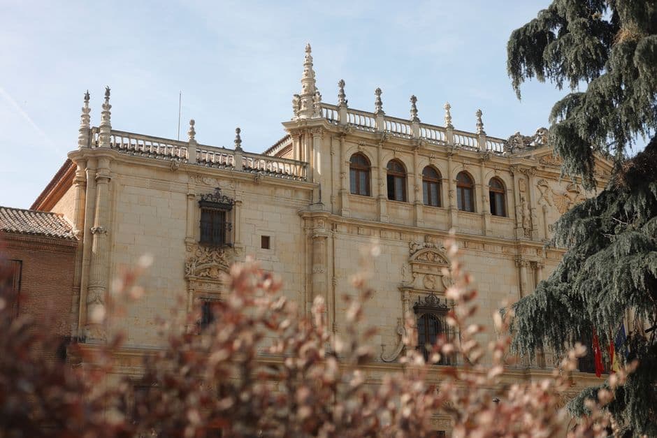 Edificio universitario histórico con fachada de ladrillo y columnas, en el chat de Alcalá de Henares