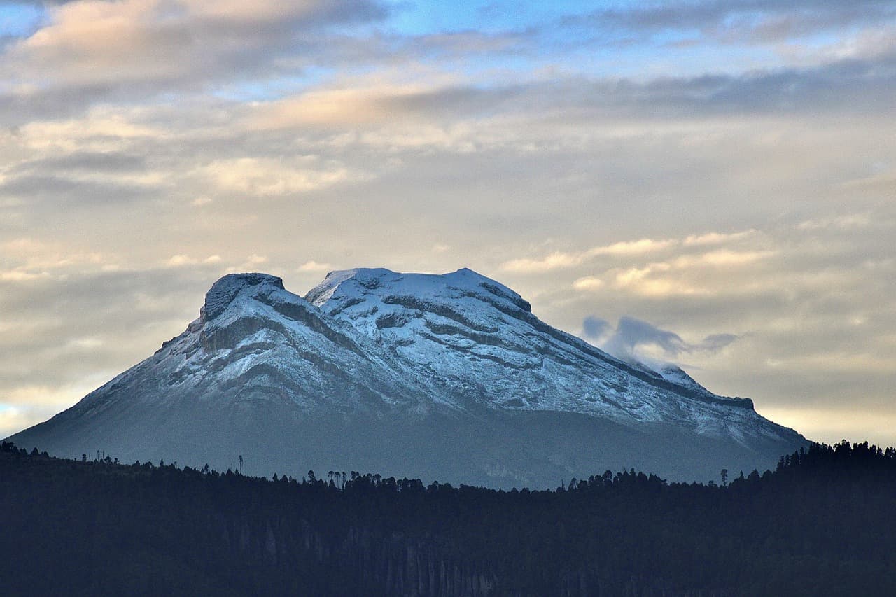 Volcán nevado con su cima bajo el cielo, en el chat de Los Reyes de Juárez