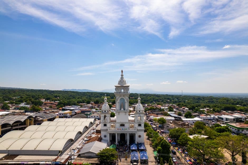 Vista aérea de una iglesia rodeada de casas, en el chat de Departamento de Morazán