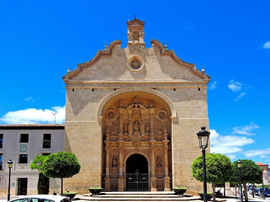 Iglesia parroquial de piedra con torre y techo rojo, en el chat de Calatayud