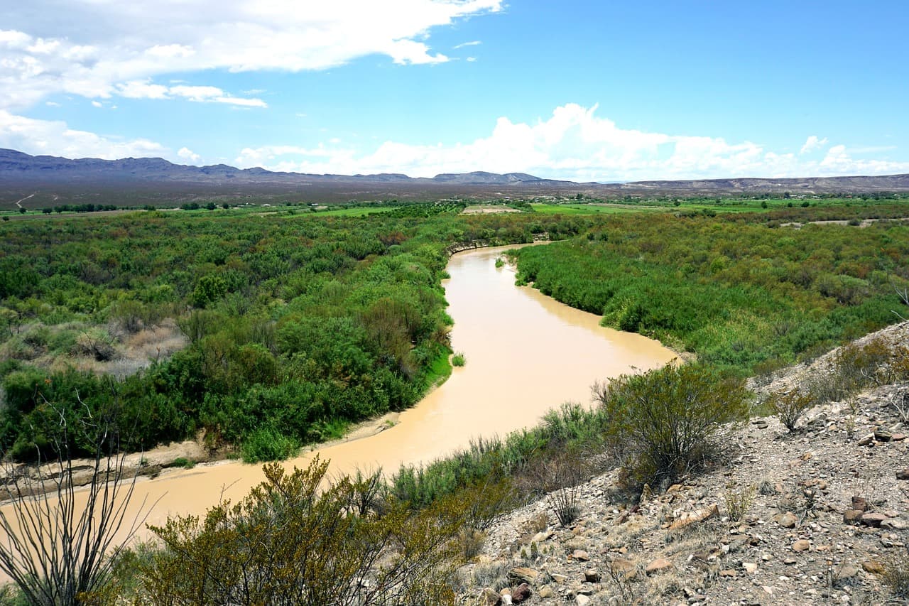 Río junto a un cañón con campo y arbustos, en el chat de Frontera