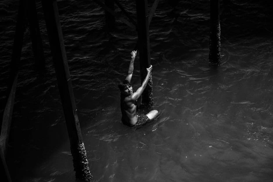 Hombre trepando bajo un muelle junto al mar, en el chat de Magdalena de Kino