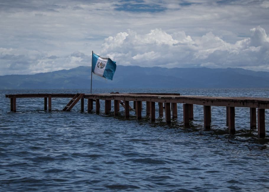Muelle de madera con bandera de Guatemala en el agua, en el chat de Escuintla