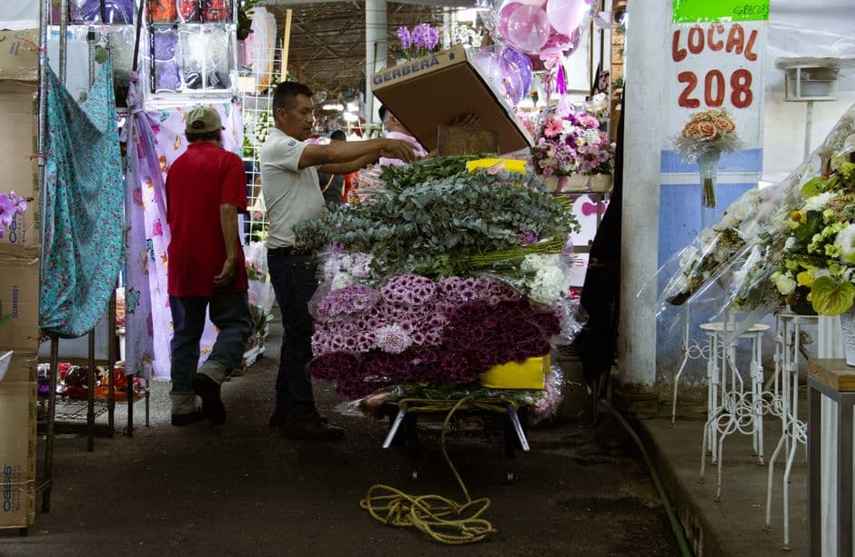 Trabajadores entre puestos de flores coloridas en mercado vibrante, en el chat de Flores, Petén