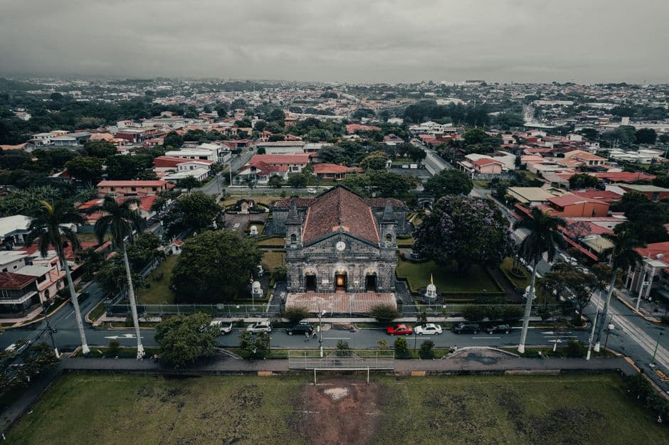 Edificios coloniales y modernos alineados en una calle bajo cielo azul, en el chat de Heredia