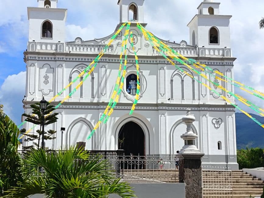 Iglesia blanca con banderas festivas en la sala de chat de Santa Tecla