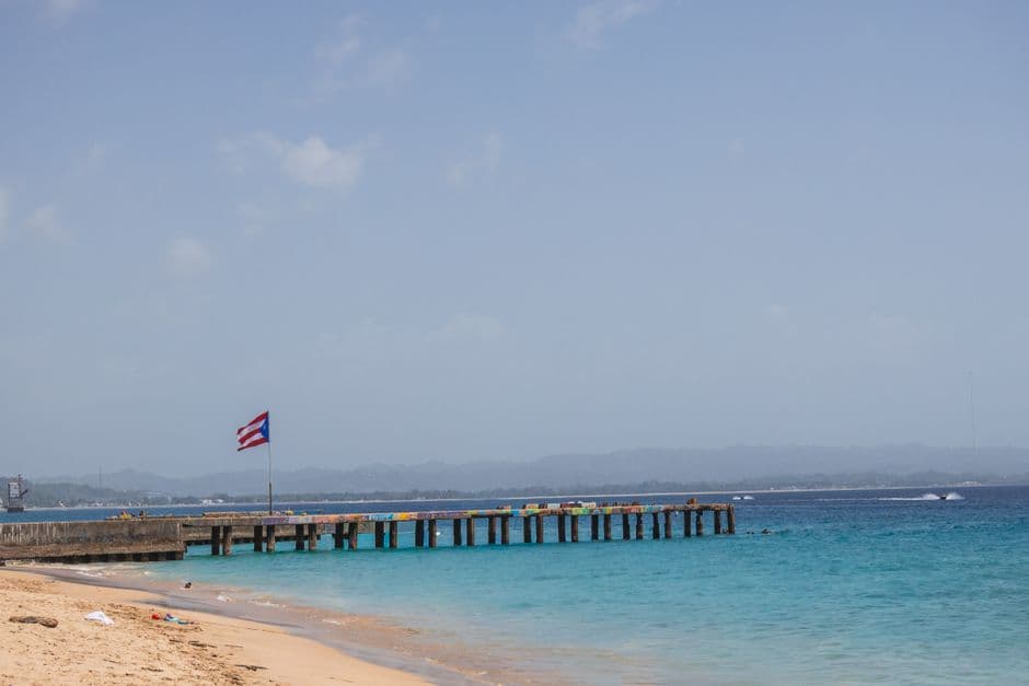 Playa tranquila con muelle y bandera, en la sala de chat de Aguadilla
