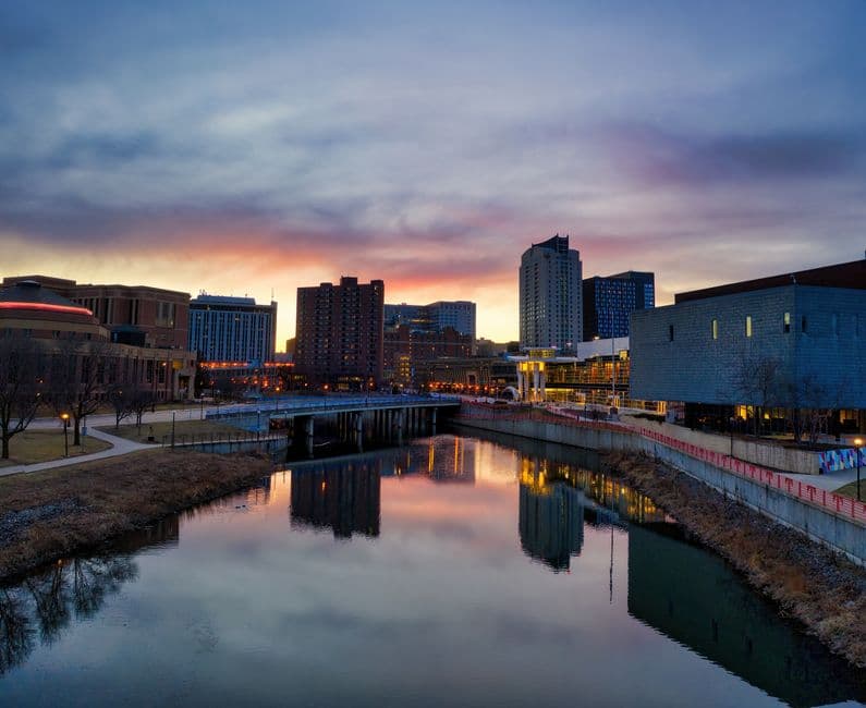 Horizonte de la ciudad junto a un río al atardecer, en el chat de Rochester