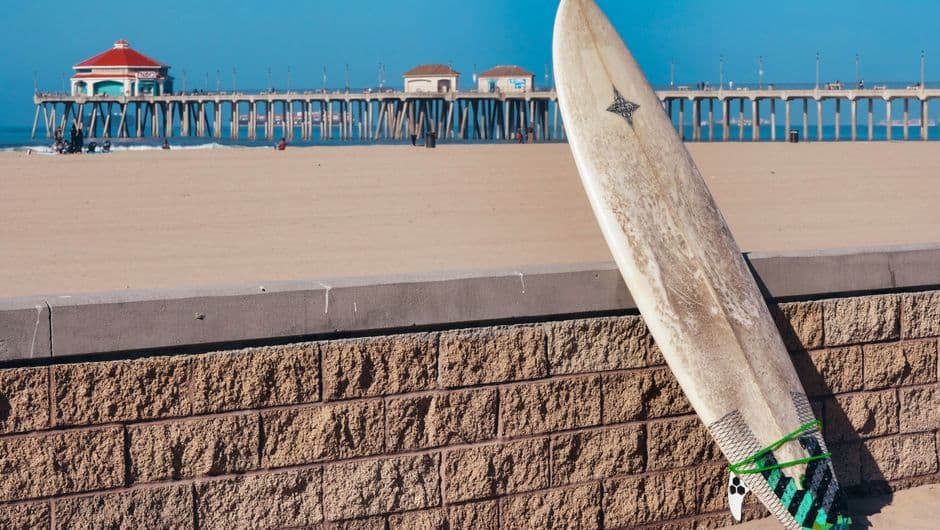 Tabla de surf apoyada contra cerca de ladrillos, en la sala de chat de Huntington Beach