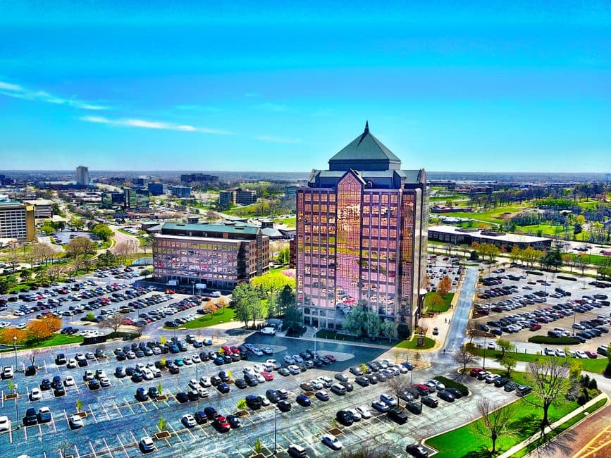 Edificio rodeado de estacionamiento bajo cielo despejado, en la sala de chat de Overland Park