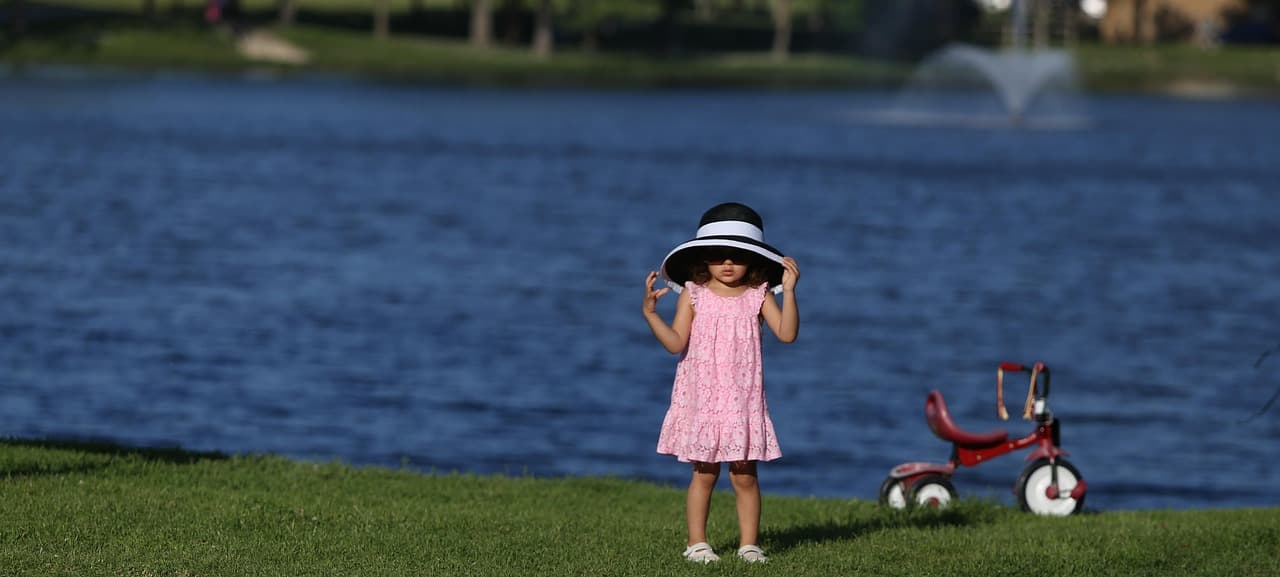 Niña pequeña con sombrero, bicicleta y vestido rojo, en la sala de chat de McKinney