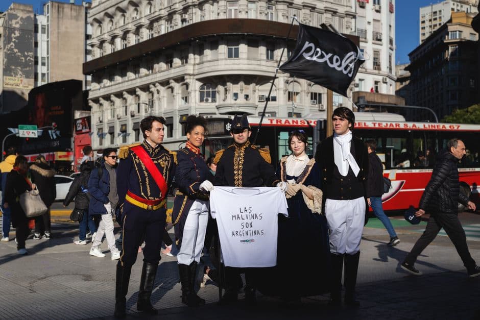 Recreadores históricos en ropa colonial caminan por una calle porteña, en el chat de La Reja