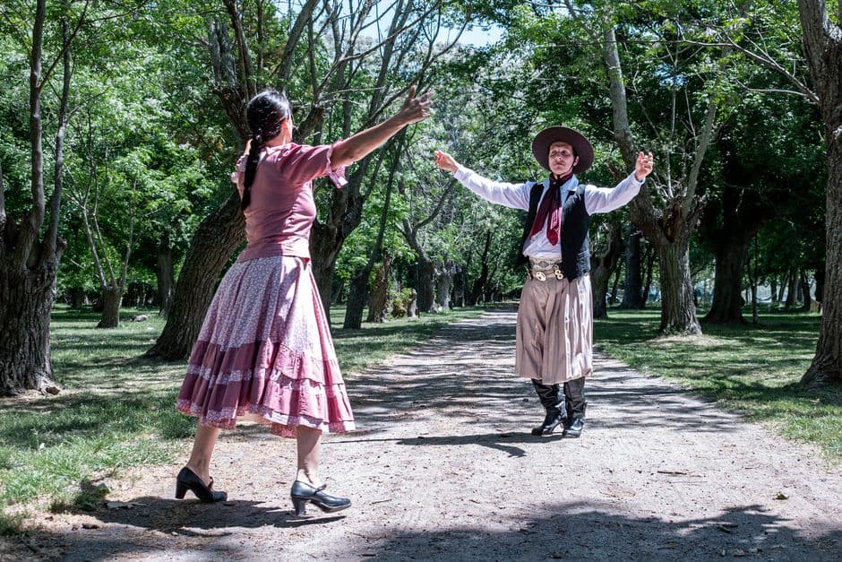 Bailarines de tango en trajes bajo árboles del parque, en la sala de chat de Chascomús