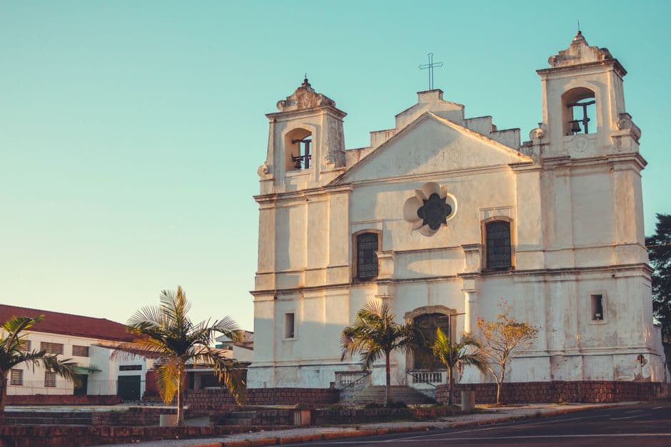 Fachada de iglesia de concreto blanco con ventanales y cruz, en el chat de Viamão