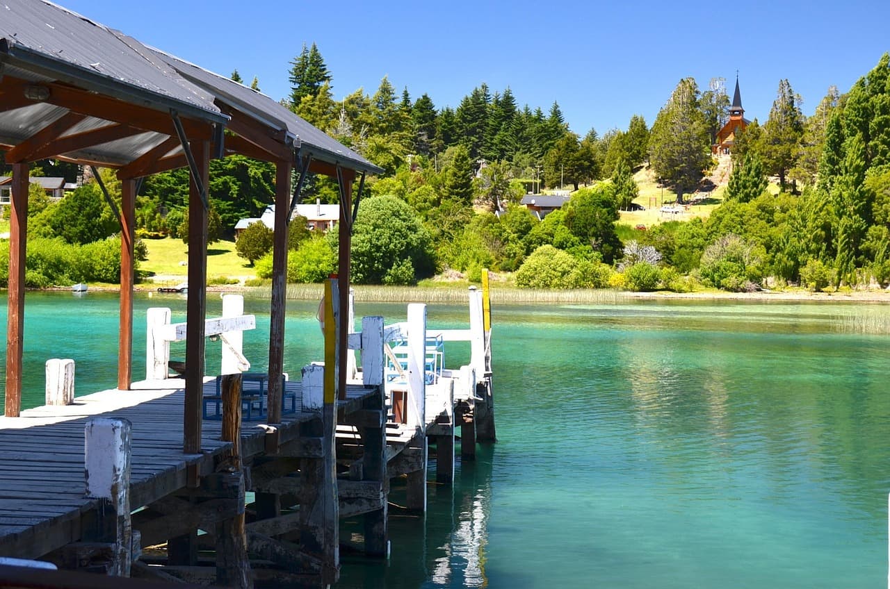 Lago azul rodeado de montañas nevadas y bosques verdes, en la sala de chat de Famaillá