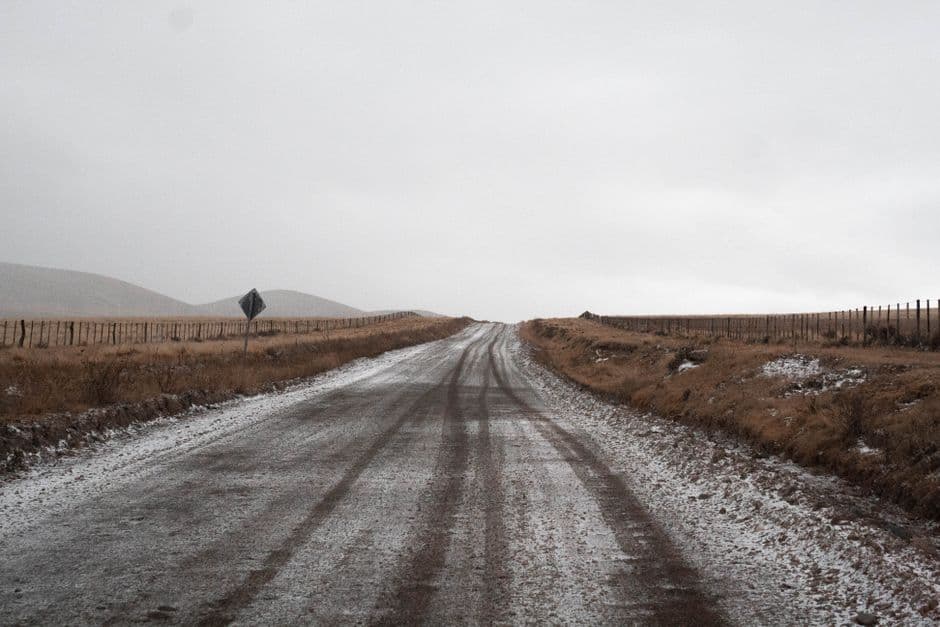Camino tierra cubierto de nieve con huellas de neumáticos, en la sala de chat de Tupungato