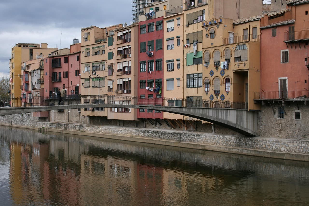 Edificios históricos y modernos de Girona bajo cielo azul, en la sala de chat de Vilablareix