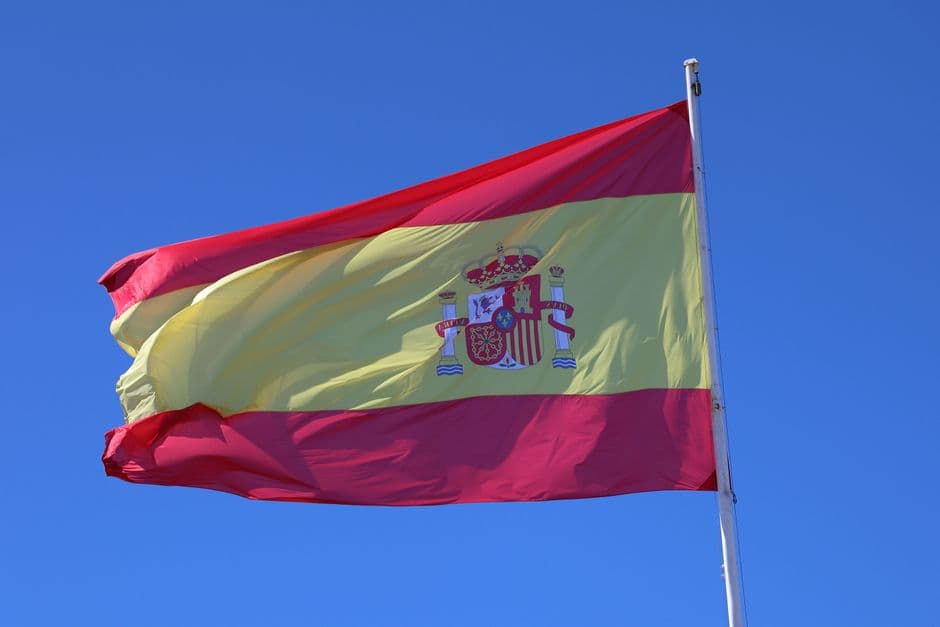 Bandera española ondeando bajo un cielo azul claro, en la sala de chat de Arriate