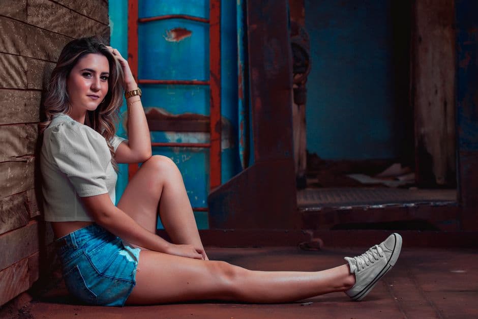 Mujer con camisa blanca y shorts vaqueros sentada, en la sala de chat de Araçatuba