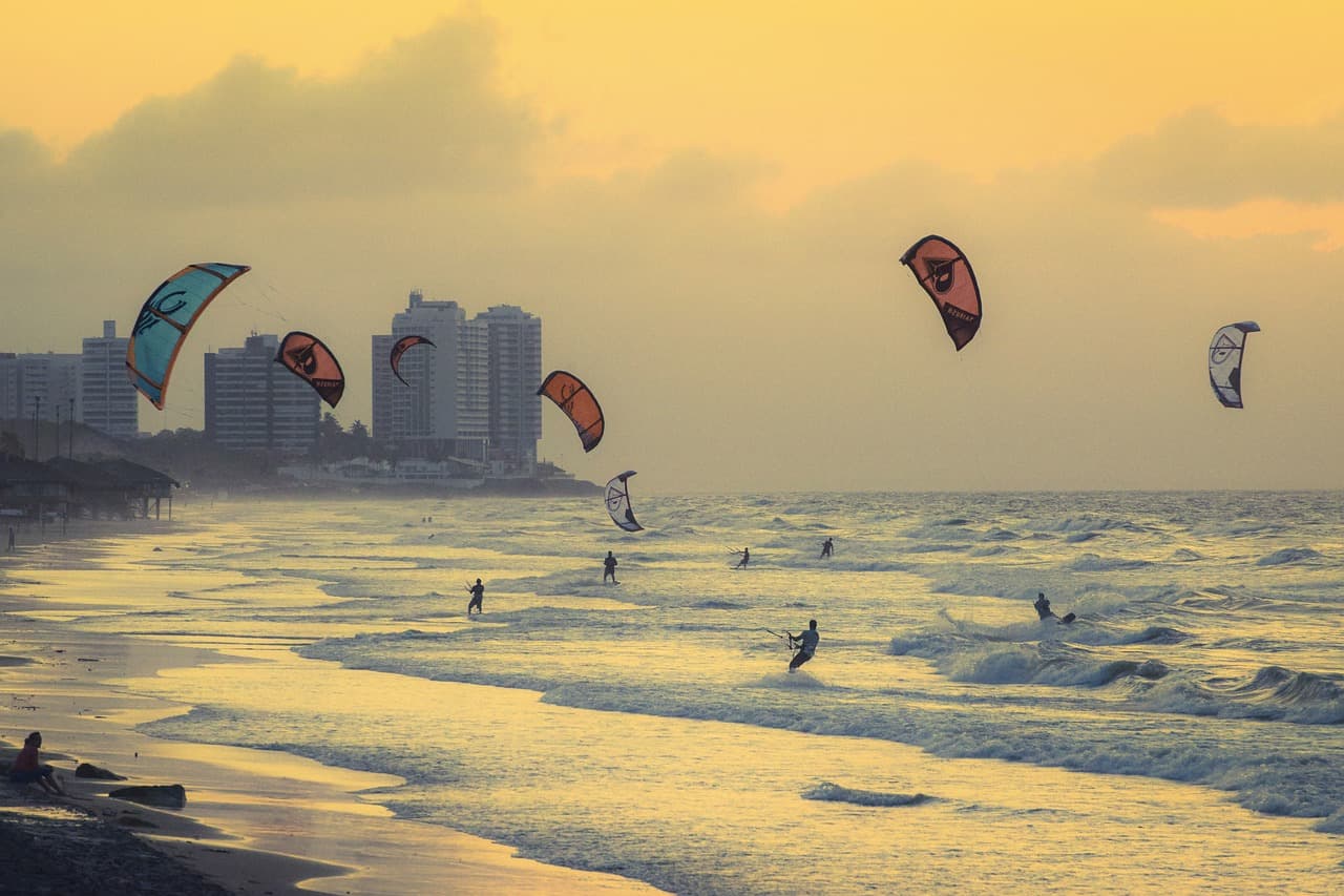 Surfista cabalgando una ola bajo el sol, con palmeras y arena, en el chat de Itaquera