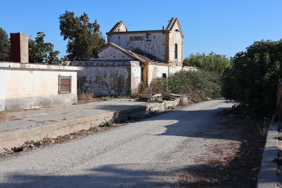 Estación de tren abandonada con vías sobrecrecidas y edificio deteriorado, en el chat de El Franco