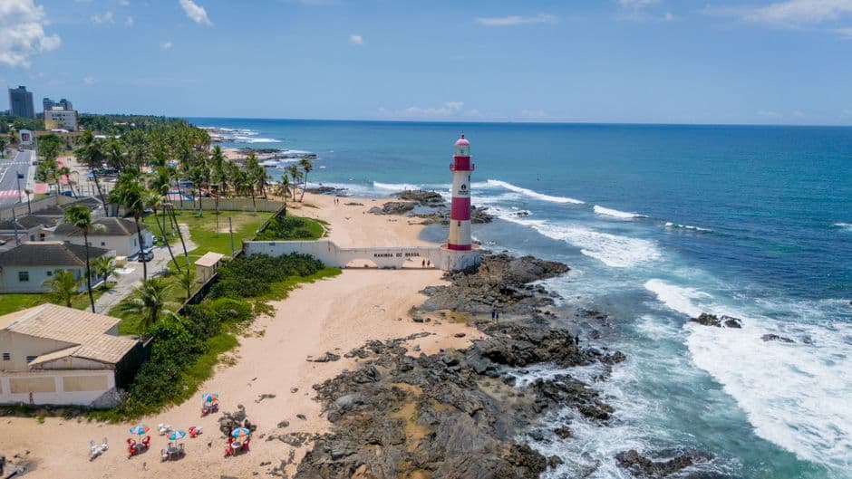 Faro blanco sobre arena y olas bajo cielo gris, en la sala de chat de Ibirité