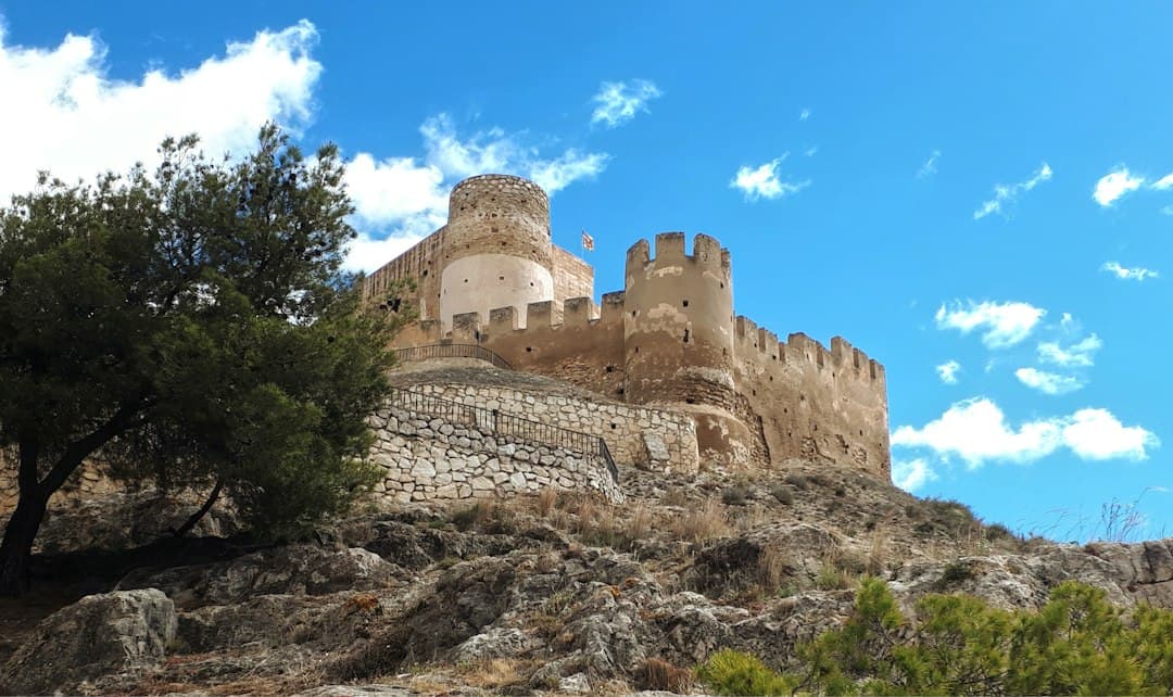 Castillo medieval sobre una colina rocosa bajo cielo despejado, en la sala de chat de Biar
