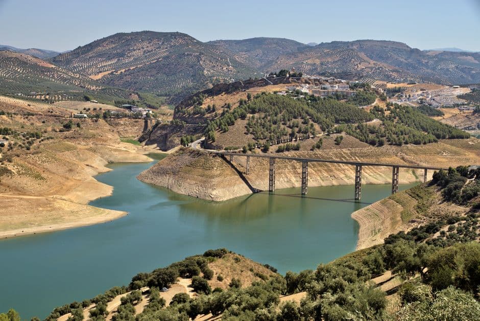 Embalse de agua rodeado de montañas bajo cielo despejado, en el chat de Iznájar