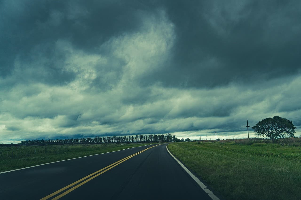 Camino entre campos bajo un cielo de nubes de tormenta, en el chat de Esquina