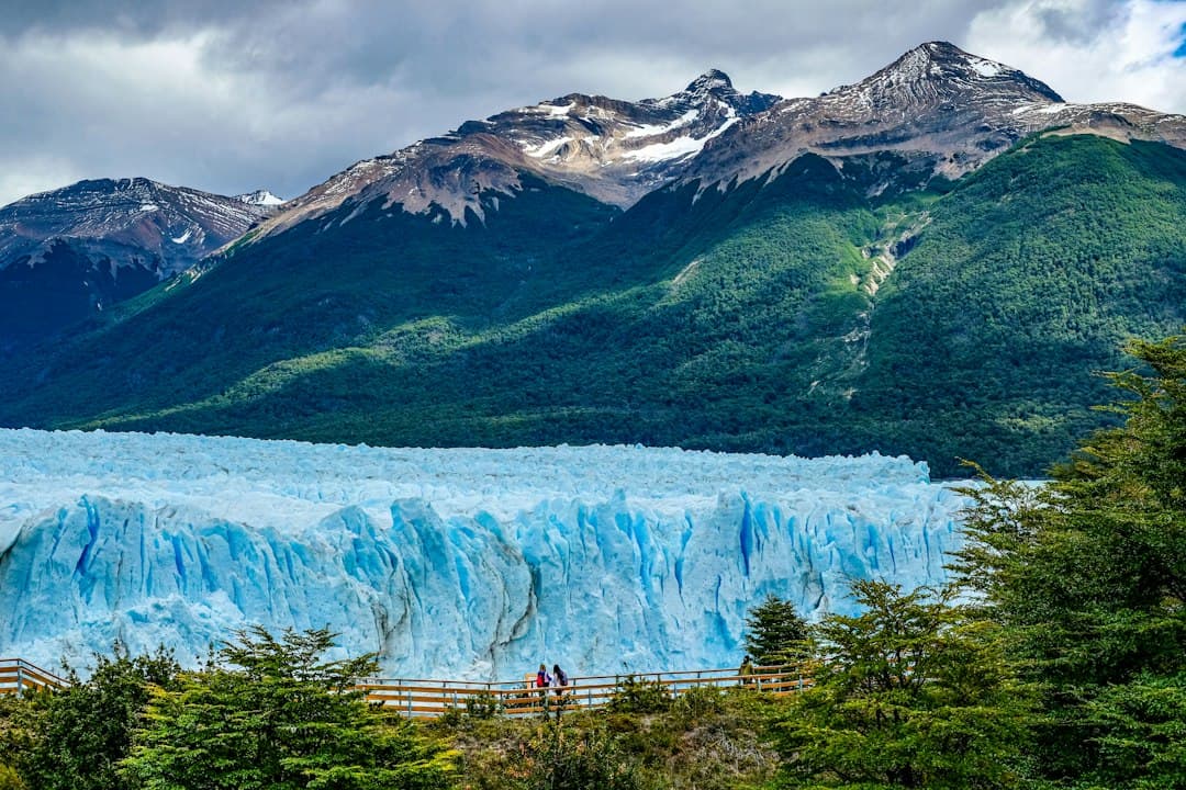 Glaciar de hielo azulado que cae sobre un lago entre montañas, en el chat de Frías