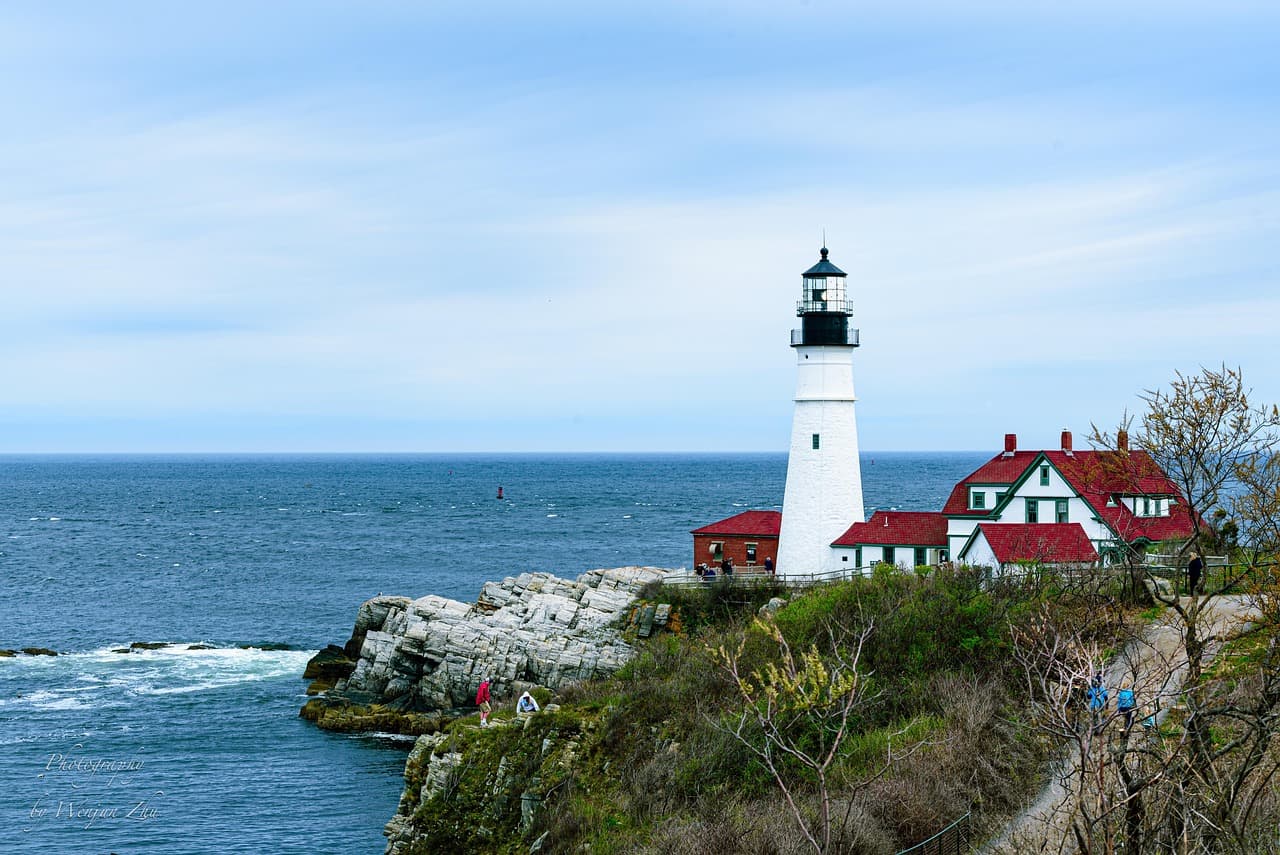 Faro blanco en acantilado, mar agitado y cielo nublado, en la sala de chat de Maine