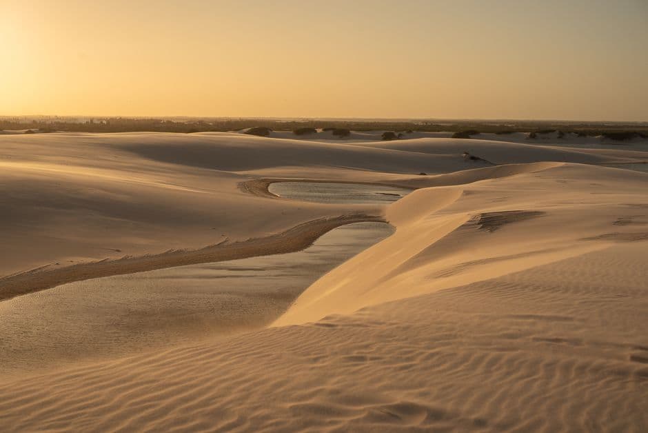 Dunas de arena iluminadas por el atardecer con cielo naranja, en el chat de Garanhuns