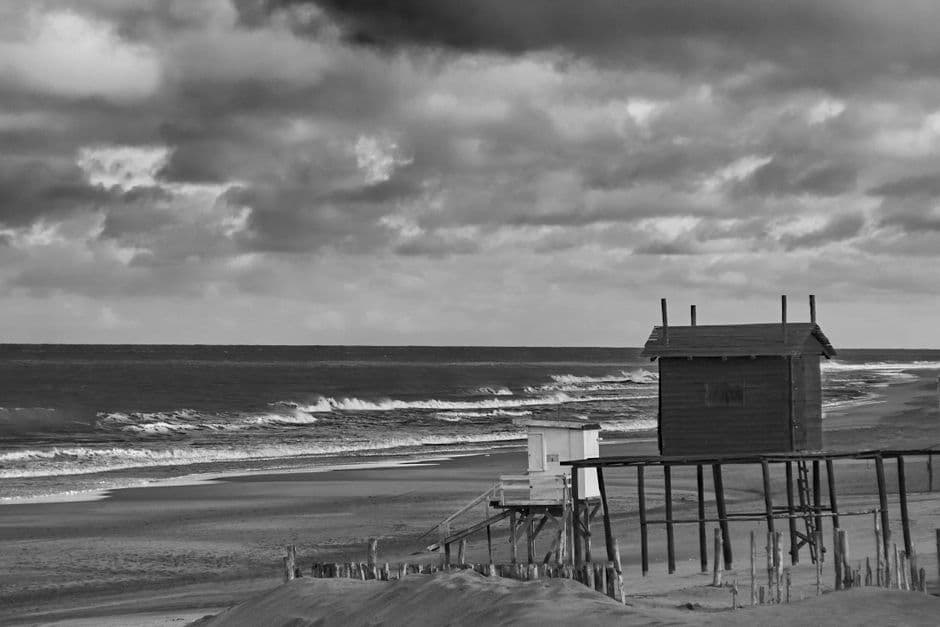 Playa con arena y olas bajo cielo gris, en la sala de chat de Villa Gesell
