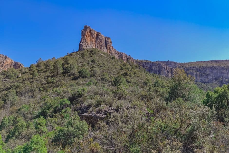Formación rocosa alta con grietas y poca vegetación, en el chat de Sierra de Yeguas