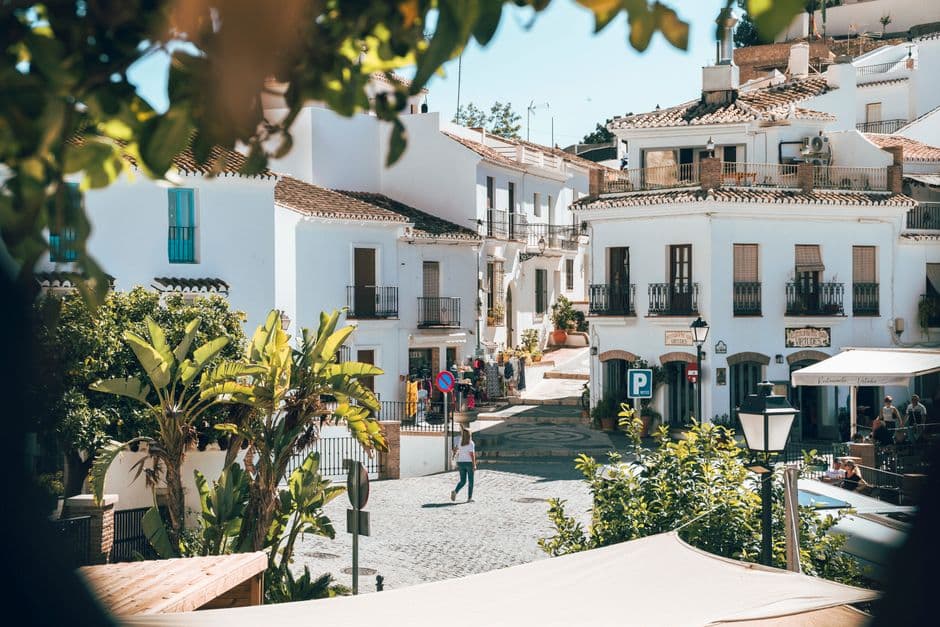 Calle estrecha de piedra con casas blancas y macetas de flores, en el chat de Frigiliana