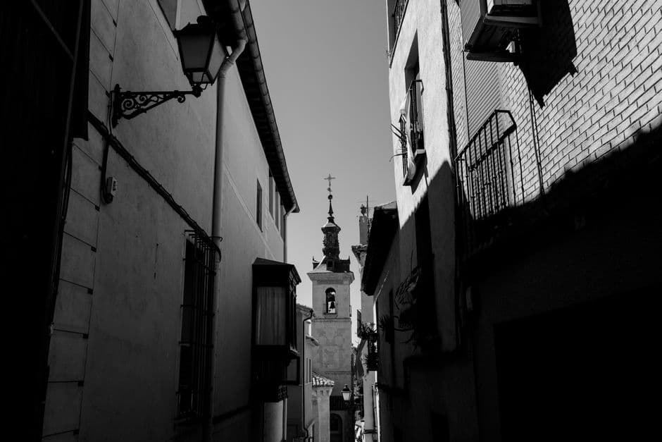 Callejón estrecho de piedra con iglesia medieval al fondo, en la sala de chat de Almenar
