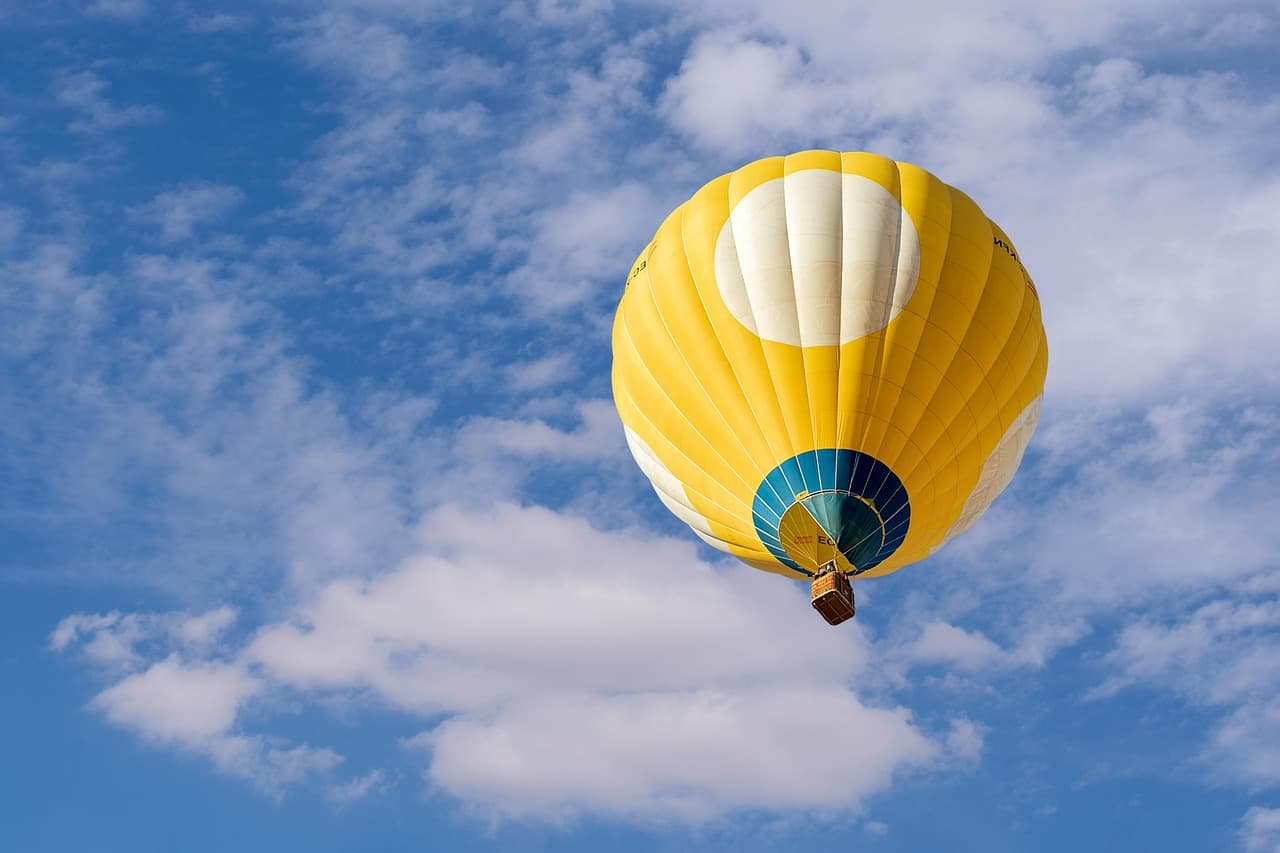 Un globo aerostático blanco flotando entre nubes suaves, en la sala de chat de El Rubio