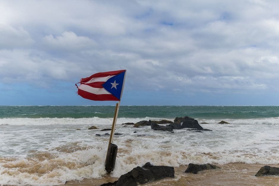 Bandera de Puerto Rico ondeando sobre la arena junto al mar, en el chat de Lajas