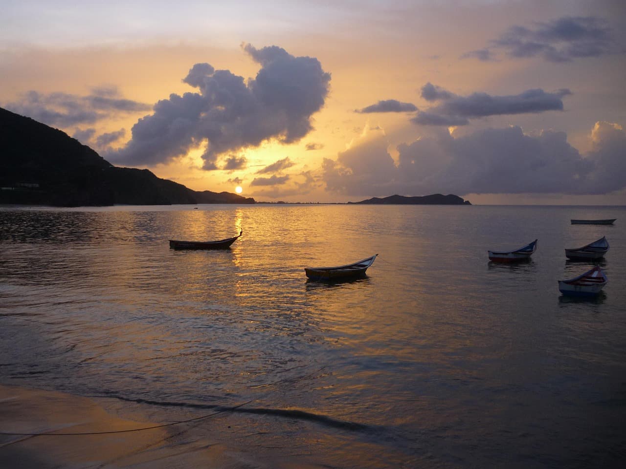 Atardecer sobre el río Caribe con cielo anaranjado y reflejo dorado, en el chat de Acosta