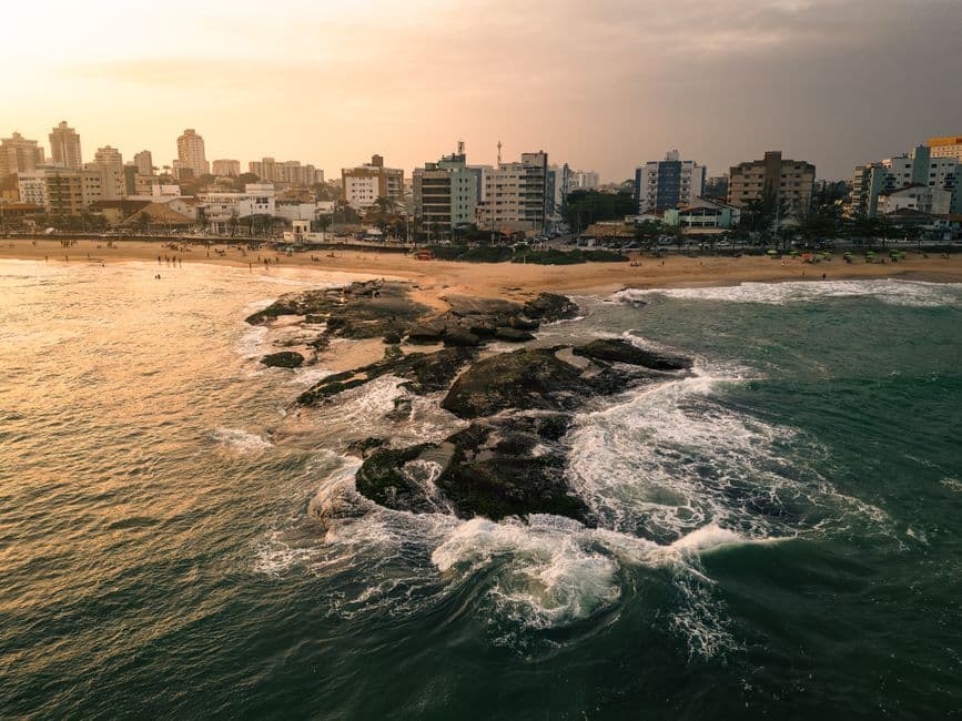 Olas rompiendo contra rocas bajo el atardecer rojo, en la sala de chat de Macaé